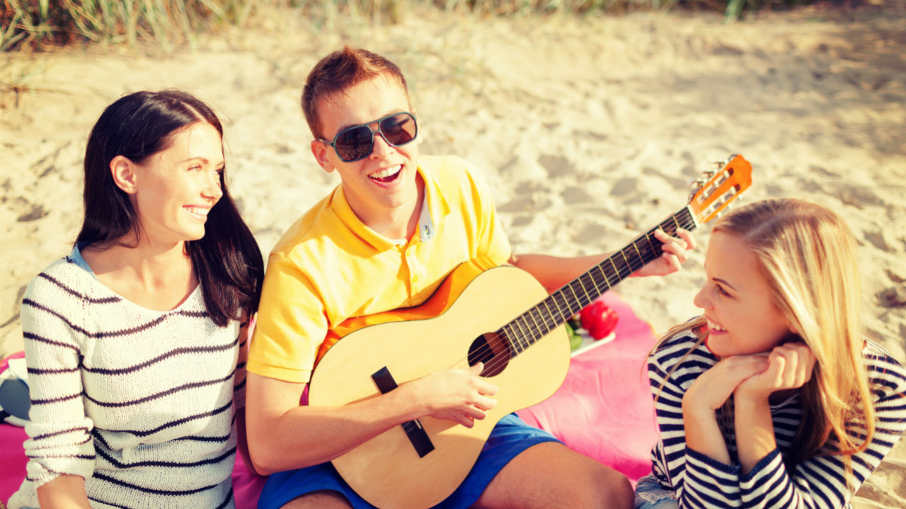 group of friends with guitar on beach