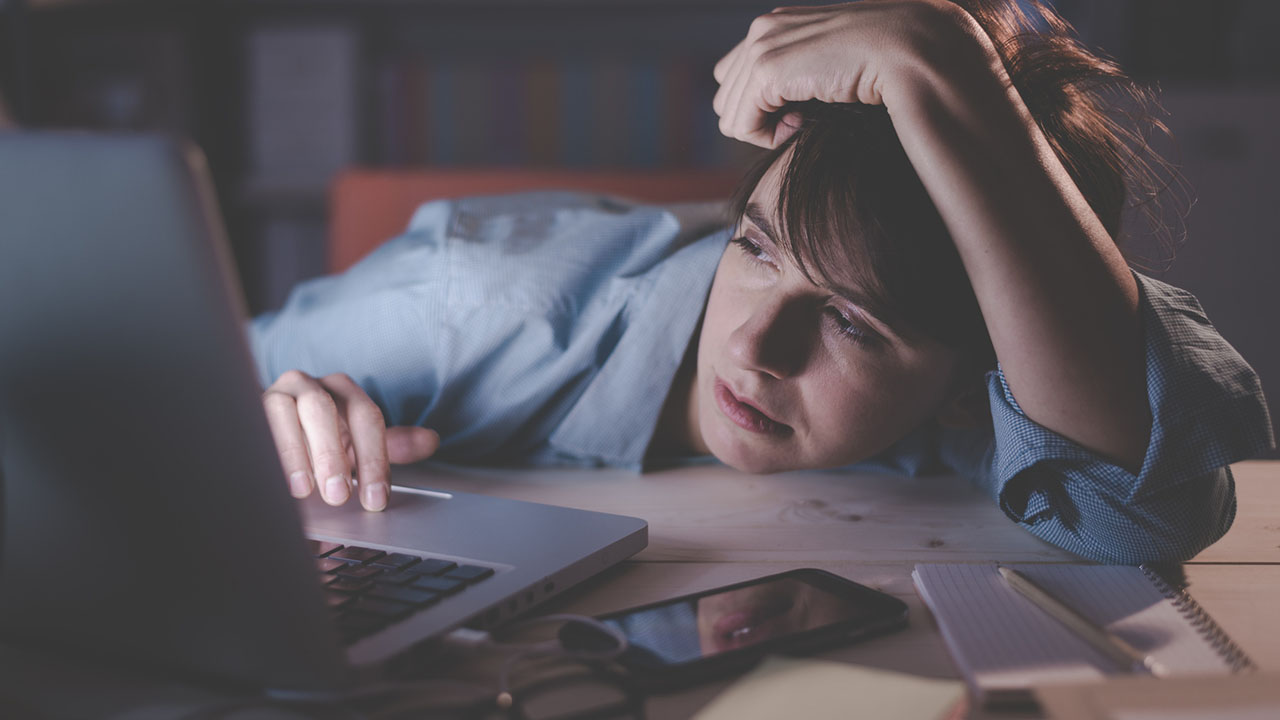 Sleepy woman uses her laptop late at night